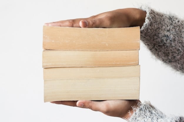 Several hands reaching towards a stack of books on a table. The books are in various colors and sizes, and the hands are diverse in skin tone and age. The background is slightly blurred, creating a sense of warmth and community.
