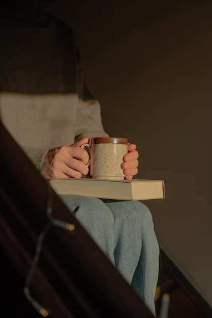 A close-up shot of two hands holding a book, with coffee mugs and reading glasses blurred in the background. The focus is on the act of reading and the warm, inviting atmosphere.