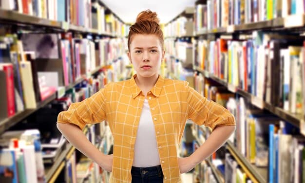 A portrait of a young, contemporary author with a thoughtful expression, surrounded by stacks of books that blend modern and classic titles. The background is a cozy reading nook, suggesting intellectual curiosity and comfort.