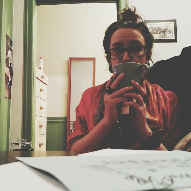 An author sitting at a coffee shop, talking animatedly and gesturing with her hands, as if sharing her experiences and insights on writing.