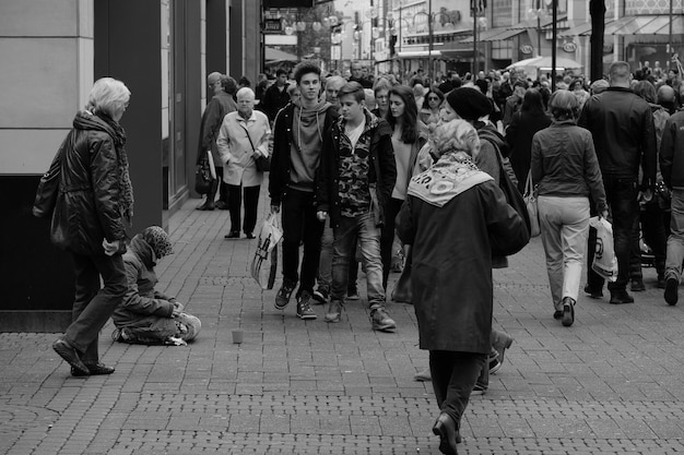 A black and white image of a crowd of people with identical clothing and blank expressions walking in the same direction, symbolizing the loss of individuality and conformity in dystopian societies.