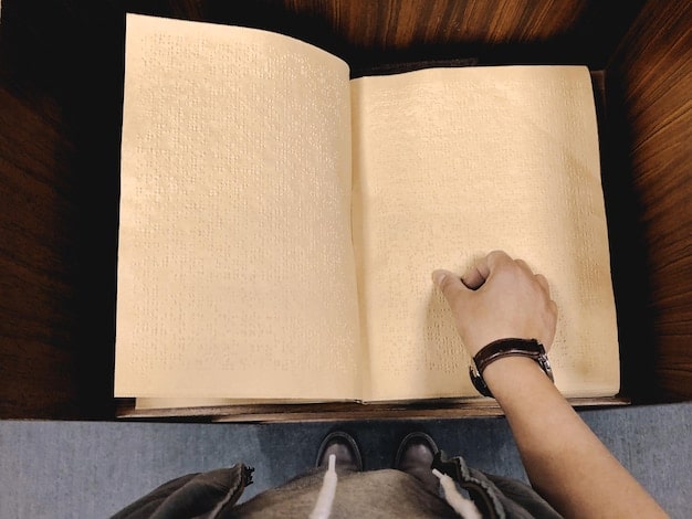 A close-up shot of a reader's hands holding an open book, with annotations and highlighted passages visible. The background is blurred, emphasizing the reader's engagement with the text. The book appears worn, suggesting it has been read multiple times.