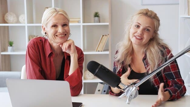 Two women sitting in a recording studio laughing and discussing different points being made.