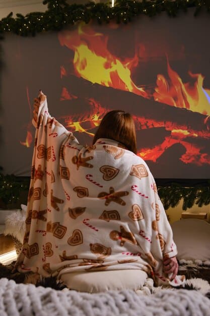 An image showing a person sitting comfortably on a couch, wrapped in a blanket, watching a movie on a large-screen TV. The room is dimly lit, with soft lighting creating a cozy and relaxed atmosphere.