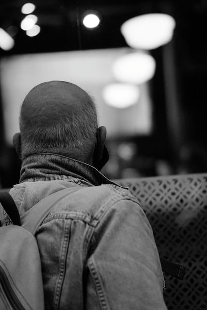 A close-up of a theater director deep in thought during a rehearsal, possibly contemplating a challenging scene or a complex character interaction. The lighting is dim, focused on the director's face to convey a sense of intensity and creative concentration.