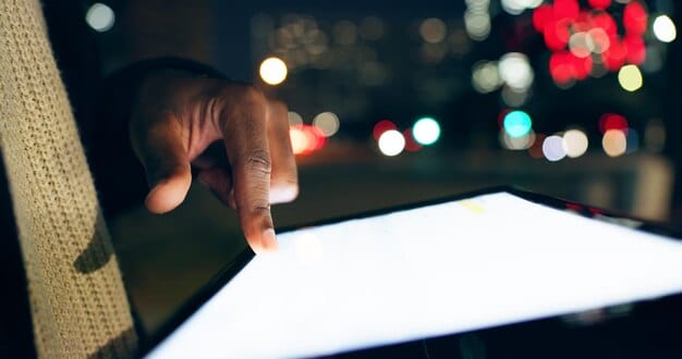 A close-up shot of a person's hand scrolling endlessly through a streaming service's menu on a tablet. The screen displays numerous movie and TV show thumbnails, showcasing the overwhelming amount of available content.