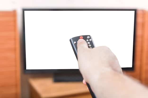 A person holding a remote control, pointing it at a screen displaying a choice panel from an interactive streaming show. The background is a blurred living room setting.