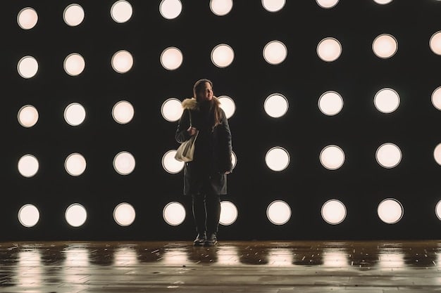 A shot of a lighting designer adjusting the lights on a theatrical stage. The stage is dark except for the focused beams of light, creating a dramatic and atmospheric effect. Various lighting instruments are visible in the background, highlighting the technical complexity of the lighting design. The image visually represents the intricacies of bringing a novel to life on stage, fitting perfectly within the theme of 'From Page to Stage: A Behind-the-Scenes Look at Adapting Novels for Theater'.