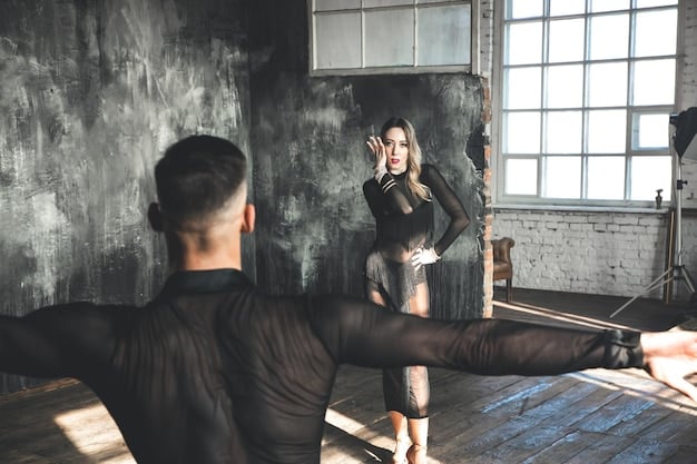 A close-up shot of a stage combat instructor demonstrating a block technique to an actor. The instructor is carefully positioning the actor's arm to deflect an incoming strike. Both are wearing comfortable rehearsal clothing in a studio with mats on the floor, emphasizing the controlled environment of Stage Combat Safety: An Inside Look at Choreography and Risk Management training.