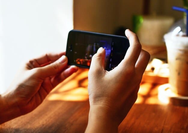 A close-up shot of a person's hands using a smartphone to stream video content. The phone screen displays a user interface of a streaming app with personalized recommendations tailored to the user's viewing history. The background is blurred to focus on the smartphone and the act of mobile streaming. The image represents accessibility and personalized Streaming Trends in 2025: What's Hot and What's Not.
